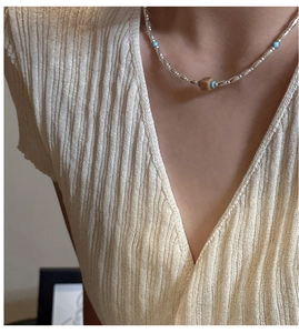 Detail of S925 silver beaded necklace with turquoise beads and brown square charm on model