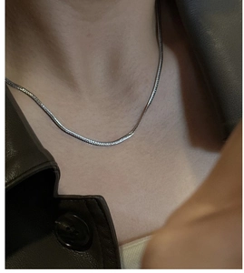 Detail of silver S925 snake chain necklace worn with a chic brown leather jacket