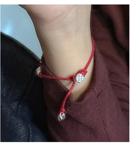Detailed view of woven red cord bracelet with S925 silver charms and Pingan Xile engraving