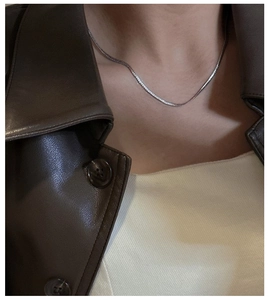 Close-up of minimalist S925 sterling silver flat snake chain worn on a leather jacket