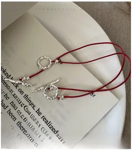 Detailed view of red cord bracelet with textured silver OT buckle on an open book