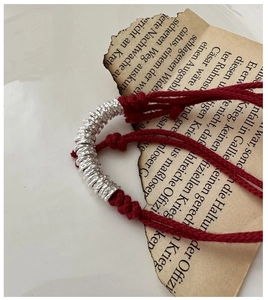 Detailed macro view of S925 sterling silver hammered rings on red braided cord bracelet