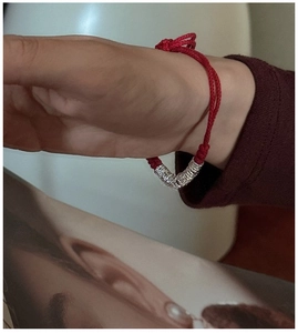 Detail of red braided silver bracelet with coiled metal beads on person's wrist