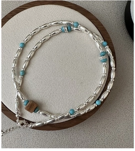 Detailed macro view of S925 silver beads and turquoise stones on a minimalist necklace