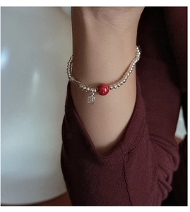 Close-up of S925 silver beaded bracelet with cinnabar charm on wrist wearing red attire