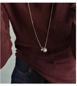Detail view of long S925 silver beaded necklace with matte ball pendant on a model