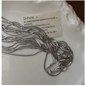 Macro detail of S925 sterling silver snake chain texture on white ceramic plate