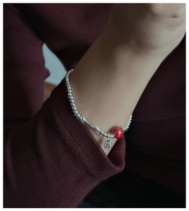 Macro shot of S925 sterling silver beaded bracelet with fish pendant and red cinnabar bead
