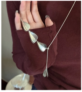 Detail of S925 silver layered leaf pendant on elegant long sweater chain necklace