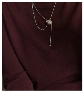 Close-up of S925 sterling silver frosted ball necklace on burgundy sweater background