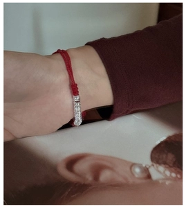 Detailed view of S925 sterling silver tube charm with pavé zircon on red woven bracelet