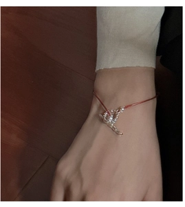 Detail of red string bracelet with silver hollow sphere pendant worn on wrist
