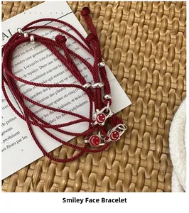 Close-up of red woven smiley face bracelet with silver beads on a lifestyle background