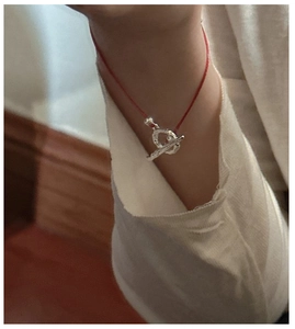Detail of red cord bracelet with silver OT toggle clasp worn on a female wrist