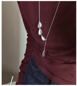 Detail of S925 sterling silver heart long necklace worn over a red sweater
