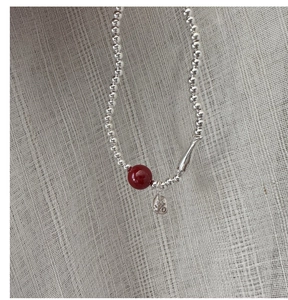 Close-up of S925 silver beaded bracelet featuring a red bead and a Fu character tag