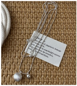 Detail of S925 sterling silver frosted and polished ball pendants on a delicate chain