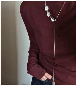 Detail of silver S925 Y-shaped necklace with teardrop pendants on a burgundy sweater