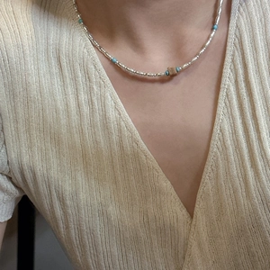 S925 silver beaded necklace with turquoise and brown stone on a beige sweater