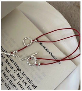 Detail of red cord bracelet with silver OT toggle clasp and hammered metal texture