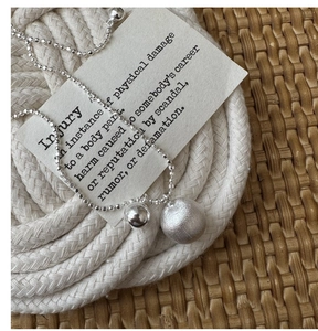 Macro detail of S925 silver necklace featuring matte and polished metal bead pendants