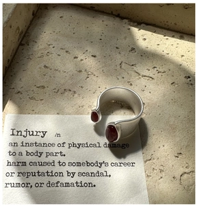 Macro detail of matte silver ring featuring red agate stones on a beige stone base