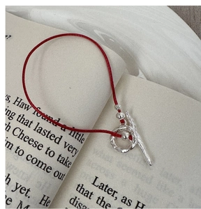 Macro detail of red woven rope bracelet with silver OT toggle clasp on book pages