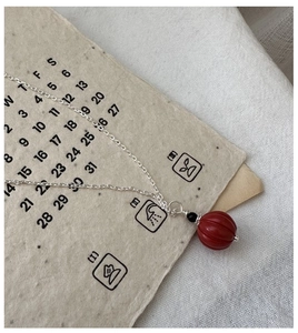 Détail du pendentif en cinabre rouge avec chaîne en argent S925 sur papier vintage