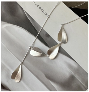 Macro view of adjustable silver snake chain necklace with four matte leaf pendants