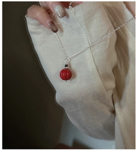 Gros plan du pendentif en perle de cinabre rouge sur une fine chaîne en argent