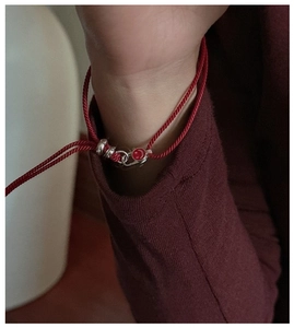 Detail of S925 sterling silver red smile pendant on minimalist woven string bracelet