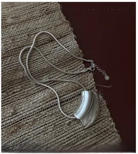 Gros plan du poinçon S925 sur le pendentif géométrique courbé de style minimaliste