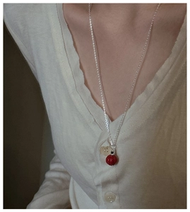 Détail d'un collier en argent S925 avec pendentif perle de cinabre rouge sur modèle