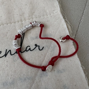 Handcrafted red string bracelet with silver hammered rings heart shaped on canvas bag
