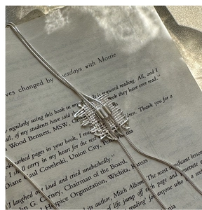 Dettaglio macro del ciondolo intrecciato in argento su una catena a serpente su un libro