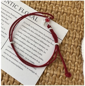 Detail of red braided smile bracelet with silver adjustable slide buckle on a vintage card