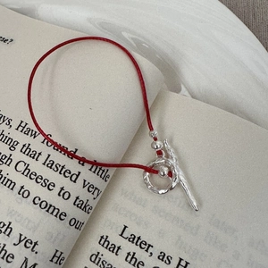 Minimalist S925 sterling silver red rope bracelet with textured OT toggle clasp on a book