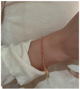 Detail of red silk thread and gold chain woven bracelet with adjustable lobster clasp