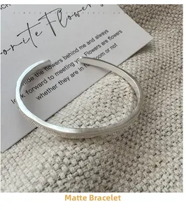 Detail of matte silver open cuff bracelet showing delicate vertical textured stripes