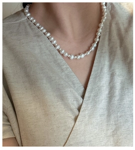 Detail of S925 silver necklace with white pearls and metallic beads on a female model neck