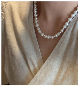 Detail of S925 silver pearl necklace with OT clasp on beige linen shirt for women