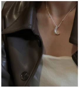 Detail of silver crescent moon necklace with hammered texture and beaded chain on model