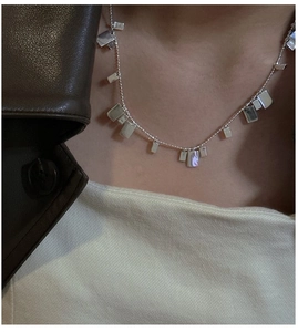 Primo piano di una collana in argento 925 minimalista con ciondoli rettangolari su una modella