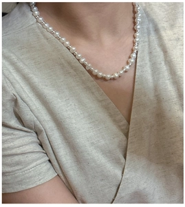 Detailed close-up of S925 silver pearl necklace with small metal spacer beads on a model