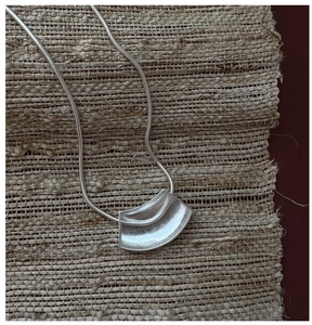 Vue détaillée du pendentif arc en argent 925 mat avec chaîne serpent sur fond tressé