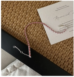 Detail of red braided cord and silver beads bracelet with lobster clasp and chain