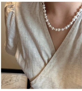 Close-up of S925 silver pearl necklace with OT clasp on model wearing linen attire