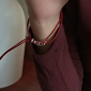 Minimalist S925 sterling silver red cord bracelet with a smiley face charm on a model