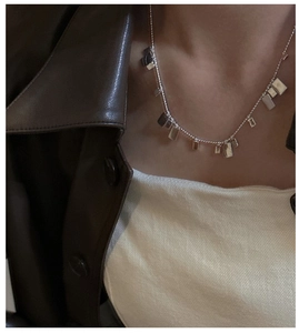 Dettaglio della collana con ciondolo quadrato in argento 925 indossata su pelle vintage