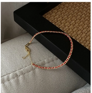 Close-up of handmade 925 silver red string bracelet with gold beads and lobster clasp